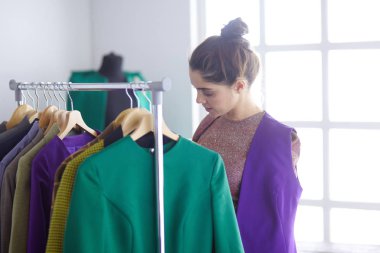 Pano raf giysi tasarımcısı ile yakınındaki beyaz arka plan üzerinde tutan güzel genç stilist