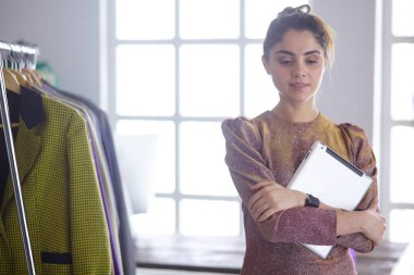 Pano raf giysi tasarımcısı ile yakınındaki beyaz arka plan üzerinde tutan güzel genç stilist