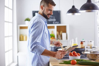 Gülümseyen ve kendinden emin şef büyük mutfakta duruyor.