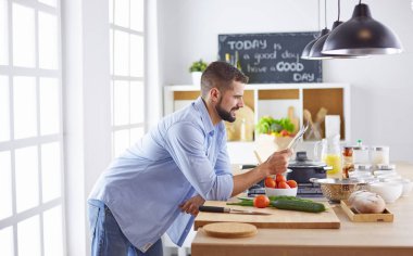 Gülümseyen ve kendinden emin şef büyük mutfakta duruyor.