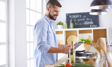 Gülümseyen ve kendinden emin şef büyük mutfakta duruyor.