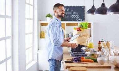 Gülümseyen ve kendinden emin şef büyük mutfakta duruyor.