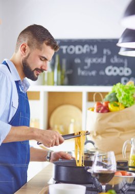 Gülümseyen ve kendinden emin şef büyük mutfakta duruyor.