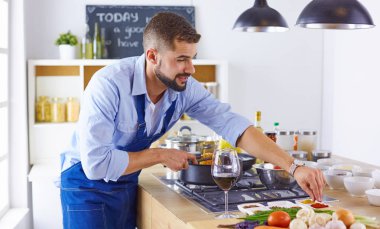Gülümseyen ve kendinden emin şef büyük mutfakta duruyor.