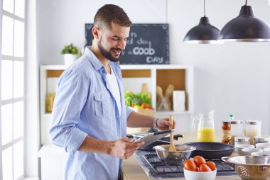 Gülümseyen ve kendinden emin şef büyük mutfakta duruyor.