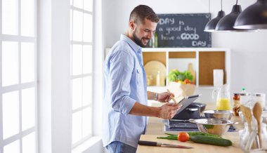 Gülümseyen ve kendinden emin şef büyük mutfakta duruyor.