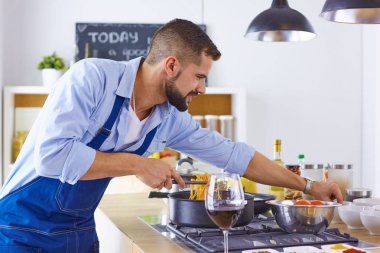 Gülümseyen ve kendinden emin şef büyük mutfakta duruyor.