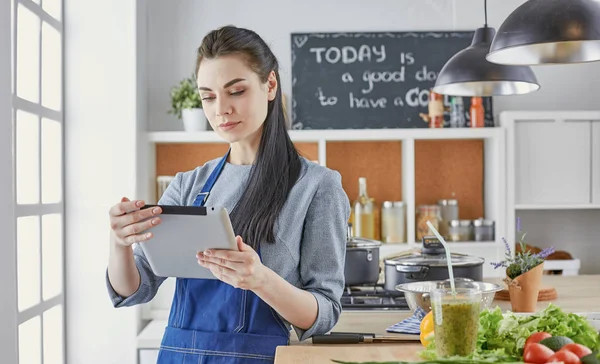 Happy woman looking recipe tablet kitchen reading cooking