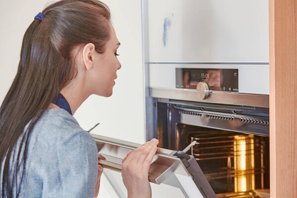 Beautiful woman in the kitchen, waiting with the front of the o