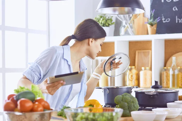 Imagem de uma jovem menina bonita de pé na cozinha e é coo — Fotografia de Stock