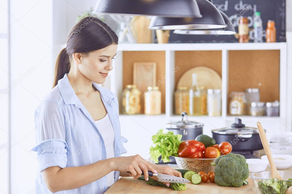 A young woman prepares food in the kitchen. Healthy food - vege