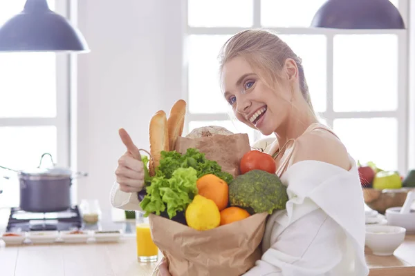 野菜提訴権と食料品の買い物袋を保持している若い女性 — ストック写真