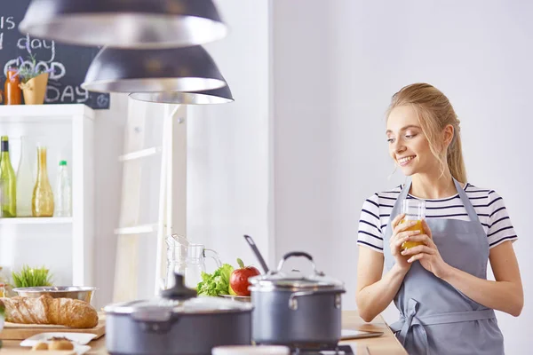 The girl at the table in the kitchen with a glass of orange jui — Stock Photo, Image