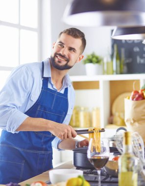 Gülümseyen ve kendinden emin şef büyük mutfakta duruyor.