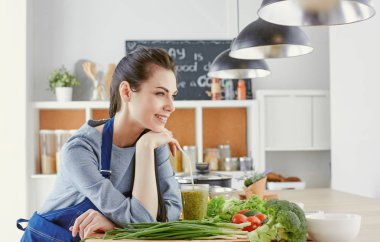 Mutlu genç kadın masanın üzerine taze sebze ile mutfakta