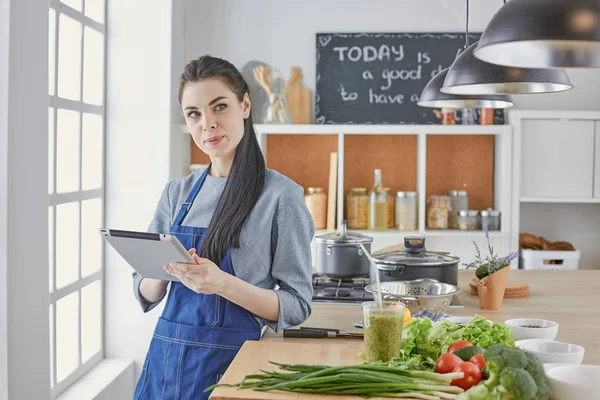 Happy woman looking recipe tablet kitchen reading cooking