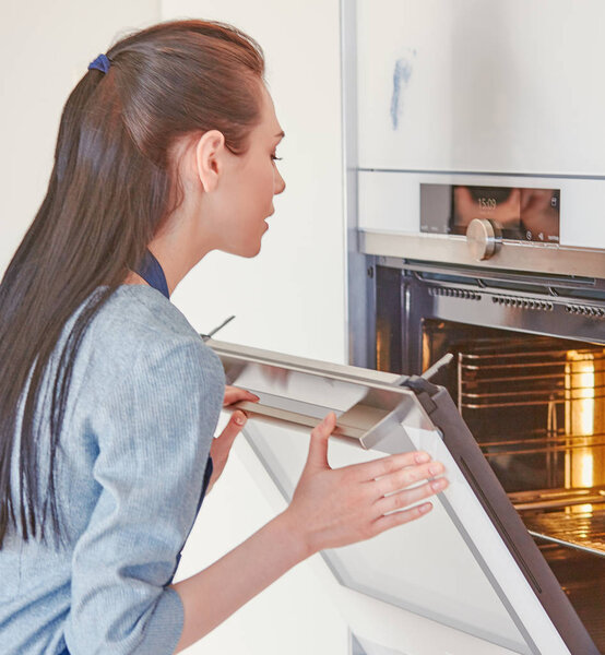 Beautiful woman in the kitchen, waiting with the front of the o