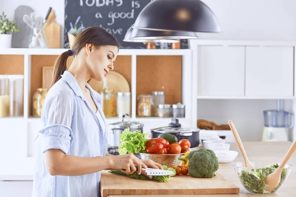 A young woman prepares food in the kitchen. Healthy food - vege