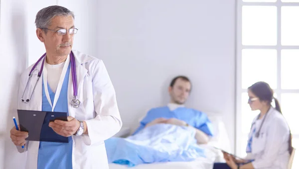 Doktor kontrola tlukot srdce pacienta v posteli s stetoskop — Stock fotografie