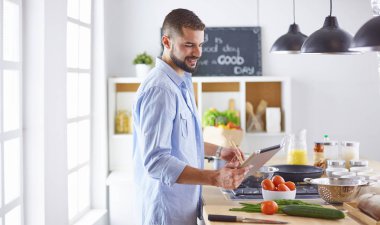 Gülümseyen ve kendinden emin şef büyük mutfakta duruyor.