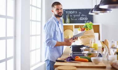 Gülümseyen ve kendinden emin şef büyük mutfakta duruyor.