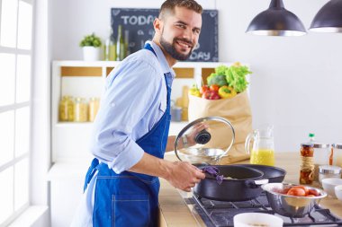 Gülümseyen ve kendinden emin şef büyük mutfakta duruyor.