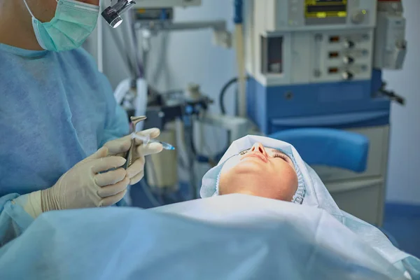 Useat lääkärit ympäröivät potilasta leikkauspöydällä työnsä aikana. Leikkaussalissa työskentelevät tiimikirurgit — kuvapankkivalokuva