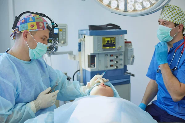 Mehrere Ärzte umgeben Patienten während ihrer Arbeit auf dem Operationstisch. Teamchirurgen bei der Arbeit im Operationssaal — Stockfoto