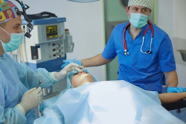 Several doctors surrounding patient on operation table during their work. Team surgeons at work in operating room — Stock Photo, Image