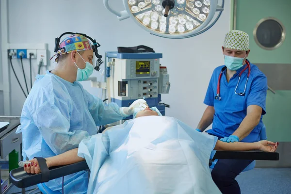 Several doctors surrounding patient on operation table during their work. Team surgeons at work in operating room — Stock Photo, Image