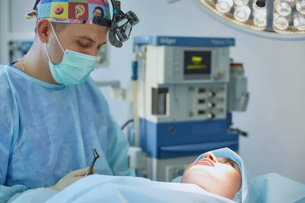 Plusieurs médecins entourant le patient sur la table d'opération pendant leur travail. Chirurgiens d'équipe au travail en salle d'opération — Photo