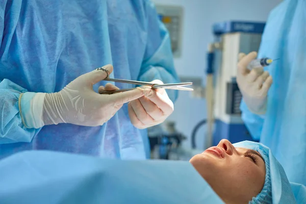 Varios médicos que rodean al paciente en la mesa de operaciones durante su trabajo. Cirujanos de equipo trabajando en quirófano — Foto de Stock