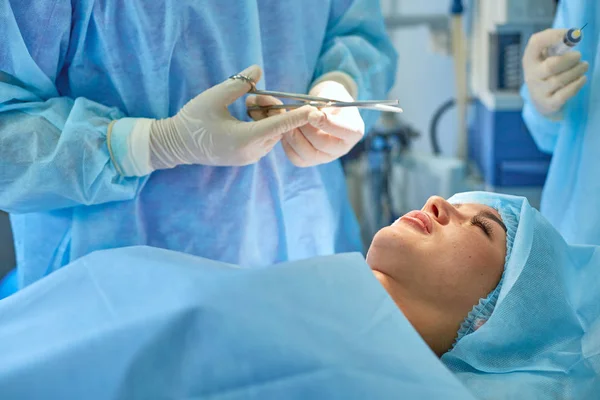 Vários médicos cercam o paciente na mesa de operação durante o trabalho. Cirurgiões de equipa a trabalhar na sala de operações — Fotografia de Stock