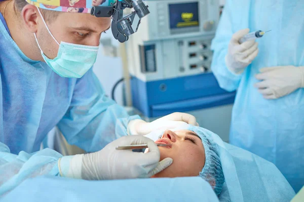 Varios médicos que rodean al paciente en la mesa de operaciones durante su trabajo. Cirujanos de equipo trabajando en quirófano — Foto de Stock