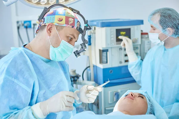 Mehrere Ärzte umgeben Patienten während ihrer Arbeit auf dem Operationstisch. Teamchirurgen bei der Arbeit im Operationssaal — Stockfoto