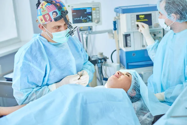 Varios médicos que rodean al paciente en la mesa de operaciones durante su trabajo. Cirujanos de equipo trabajando en quirófano — Foto de Stock