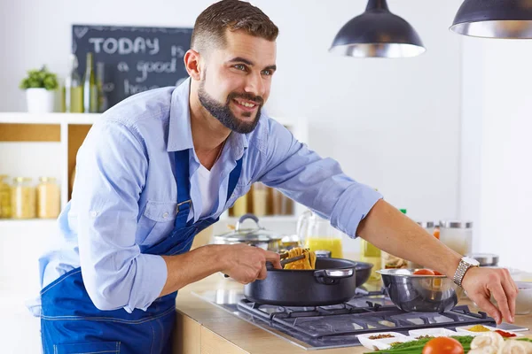 Усміхнений і впевнений шеф-кухар стоїть на великій кухні — стокове фото