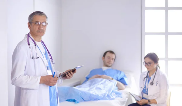 Врач проверяет сердцебиение пациента в постели стетоскопом — стоковое фото