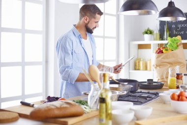 Gülümseyen ve kendinden emin şef büyük mutfakta duruyor.