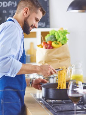 Gülümseyen ve kendinden emin şef büyük mutfakta duruyor.