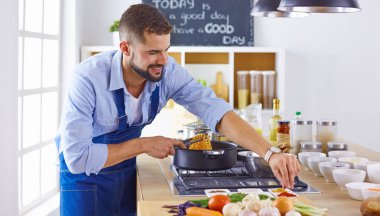 Gülümseyen ve kendinden emin şef büyük mutfakta duruyor.