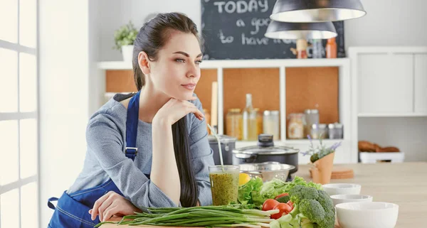 テーブルの上の新鮮な野菜とキッチンで幸せな若い女 — ストック写真