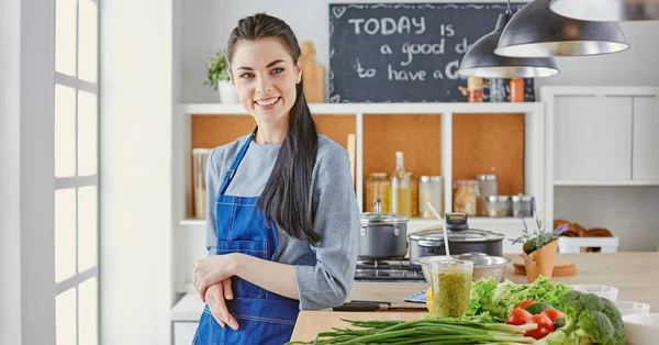 テーブルの上の新鮮な野菜とキッチンで幸せな若い女 — ストック写真