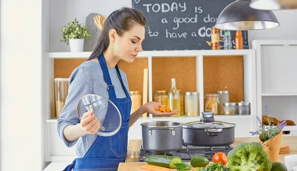 Hermosa chica está degustando comida y sonriendo mientras se cocina en kit — Foto de Stock