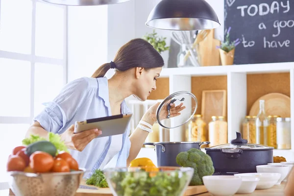 Imagem de uma jovem menina bonita de pé na cozinha e é coo — Fotografia de Stock