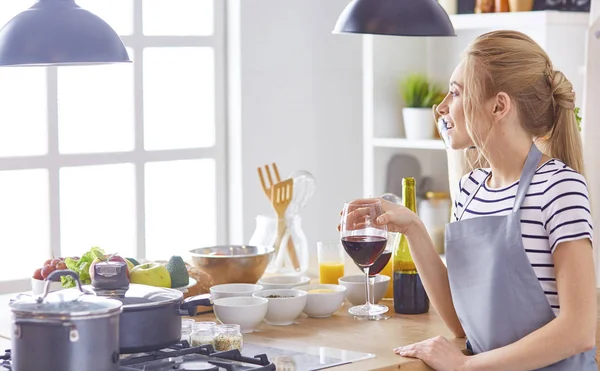 Красивая женщина на кухне пьет красное вино — стоковое фото