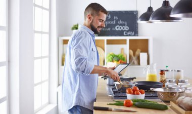 Gülümseyen ve kendinden emin şef büyük mutfakta duruyor.