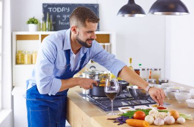 Gülümseyen ve kendinden emin şef büyük mutfakta duruyor.