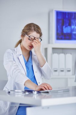 Genç kadın doktor bilgisayar ile çalıştıktan sonra yorgun