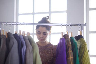 Pano raf giysi tasarımcısı ile yakınındaki beyaz arka plan üzerinde tutan güzel genç stilist